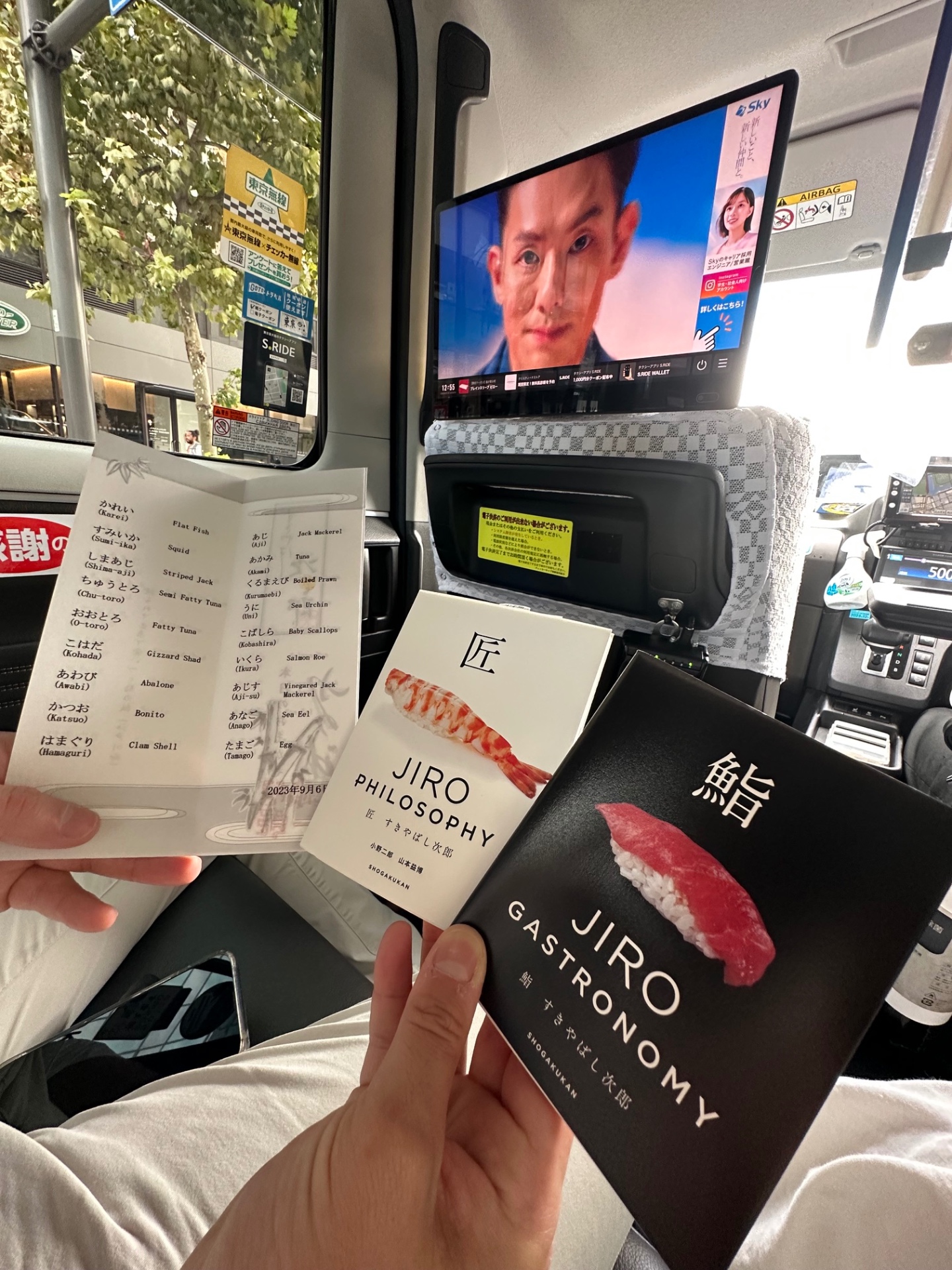 The Sukiyabashi Jiro menu alongside the Jiro Philosophy and Jiro Gastronomy books in the back of a Tokyo taxi
