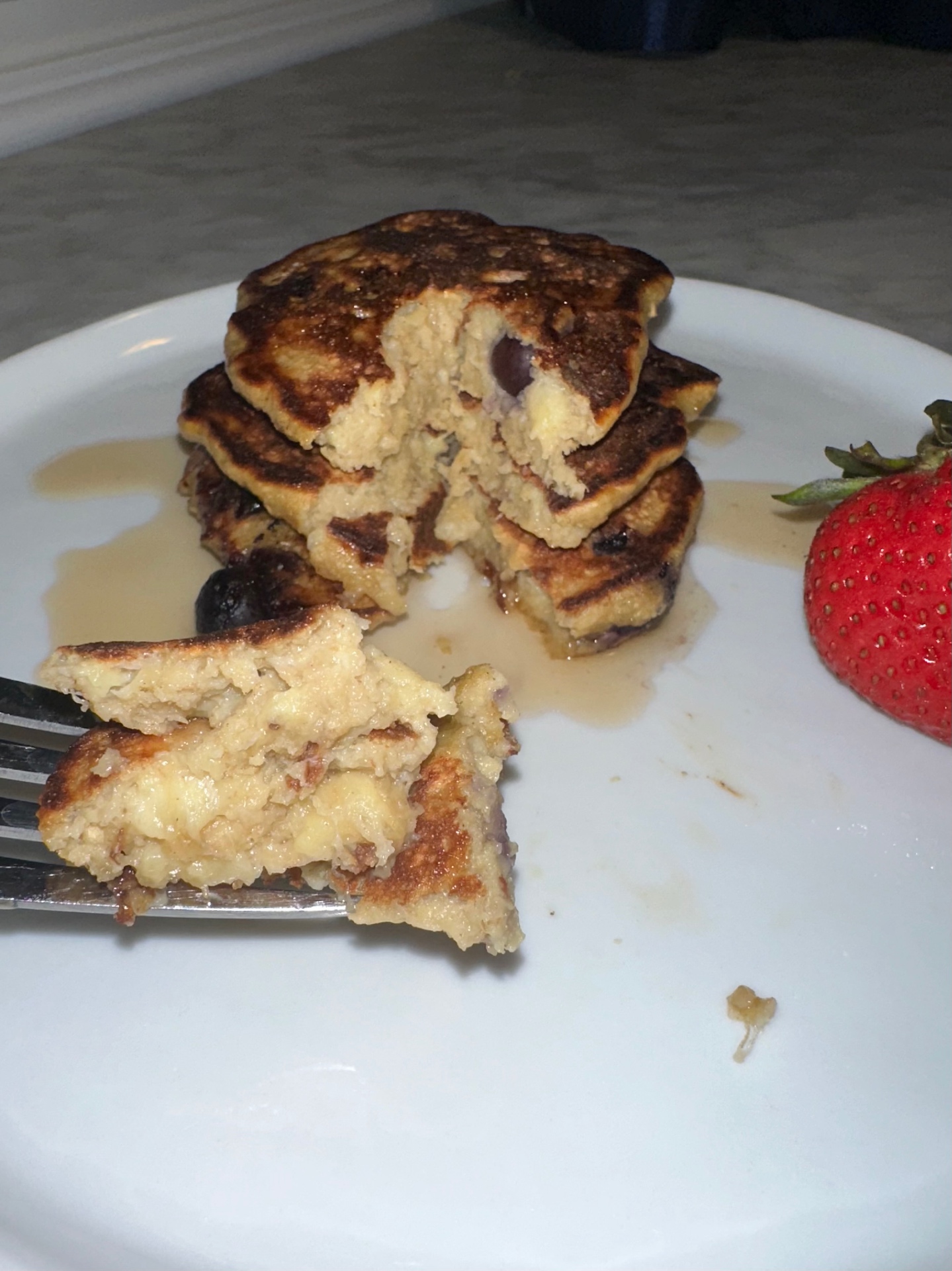 A forkful cut from banana blueberry pancakes showing the soft center and melted blueberries