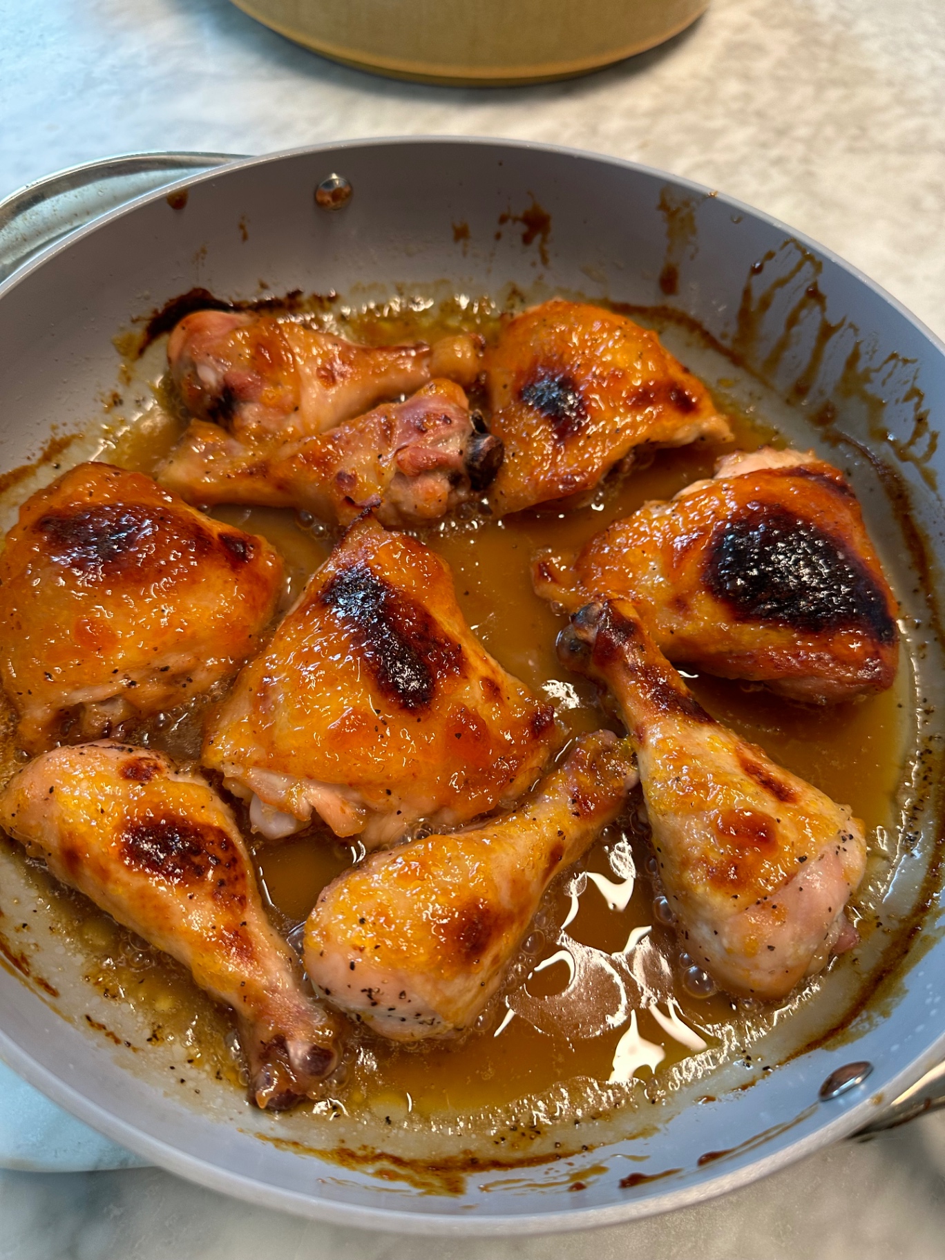 Golden roasted chicken pieces glazed with marmalade in an oven safe pan