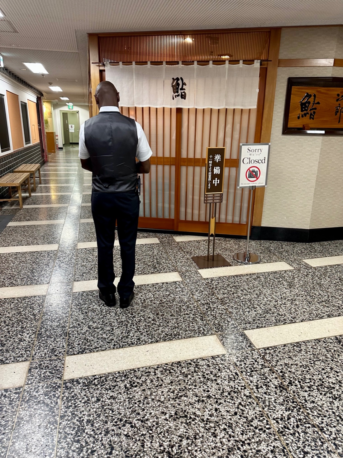 The noren curtain and sliding wooden doors of Sukiyabashi Jiro before opening, with a Sorry We're Closed sign out front
