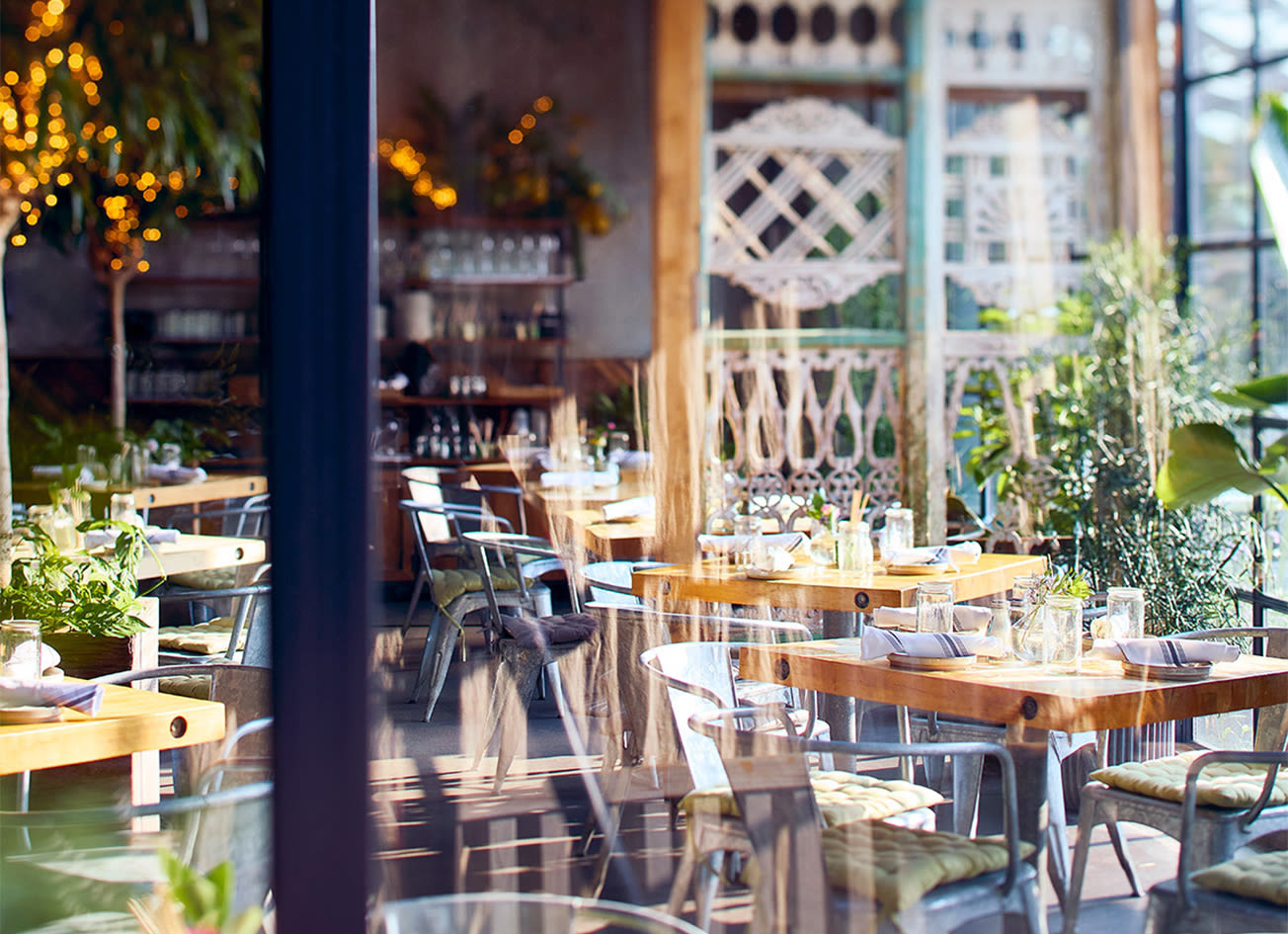 The sunlit garden café dining room at Terrain in Westport, Connecticut, with wood tables, plants, and string lights